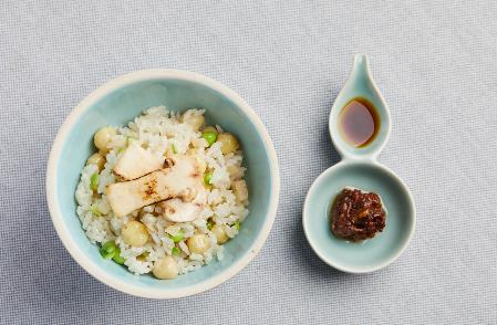A bowl of rice and vegetables with a spoon and sauce Description automatically generated