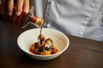 A person pouring syrup into a bowl of food Description automatically generated
