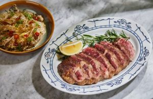 A plate of meat and a bowl of noodles Description automatically generated